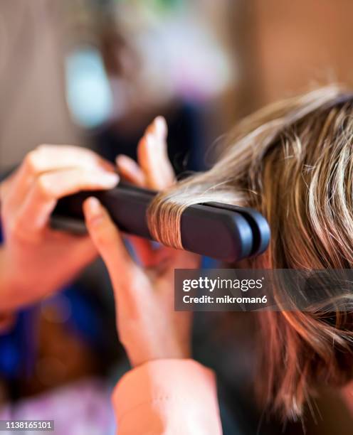 hairdresser curling womens hair at a salon - hair curlers stockfoto's en -beelden