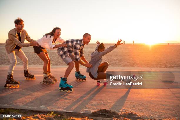 vrienden rolschaatsen op de promenade in venice beach-santa monica promenade-los angeles, verenigde staten - rolschaatsen schaats stockfoto's en -beelden