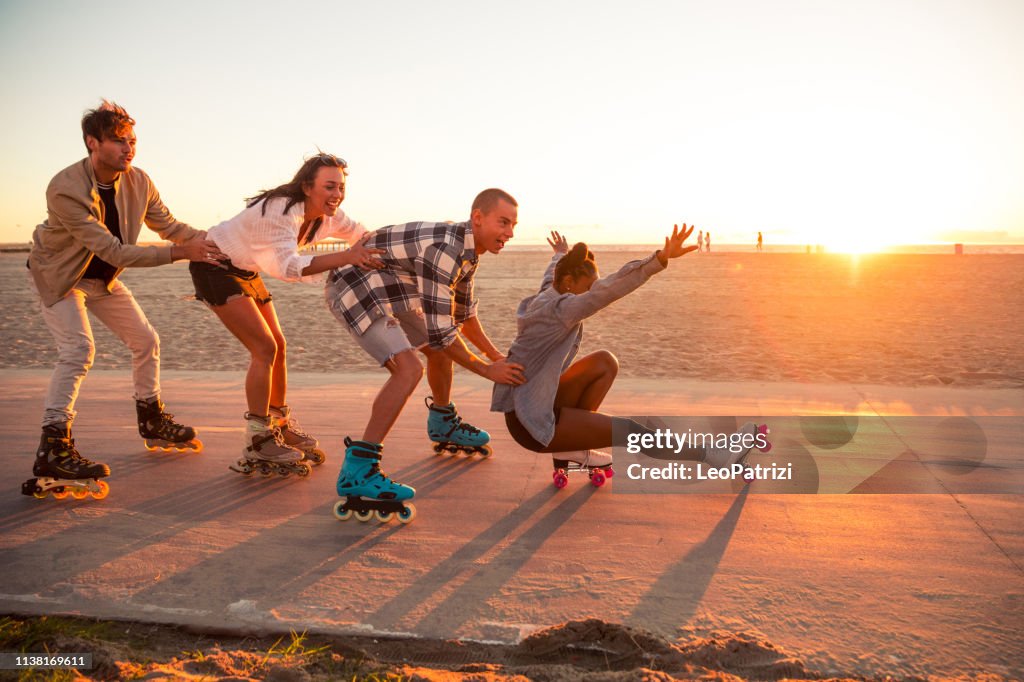 Friends roller skating on the boardwalk in Venice Beach - Santa Monica promenade - Los Angeles, USA