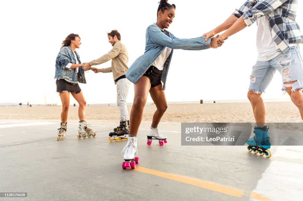 Friends roller skating on the boardwalk in Venice Beach - Santa Monica promenade - Los Angeles, USA