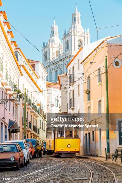 yellow tram on the narrow street of alfama district in lisbon, portugal - portugal stockfoto's en -beelden