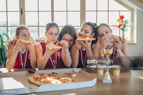 meisjes basketbal spelers eten pizza met coach na het winnen van een trofee - awards lunch stockfoto's en -beelden