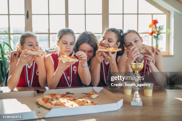 girls basketball players eating pizza with coach after wining a trophy - pizza party stock pictures, royalty-free photos & images