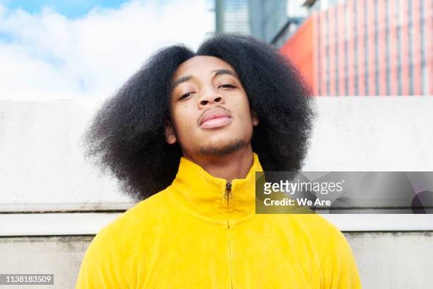 confident portrait of young man in the city - afro frisur stock-fotos und bilder
