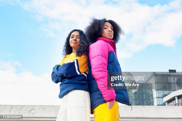 friends standing back to back, looking at camera - multi colored jacket stock pictures, royalty-free photos & images