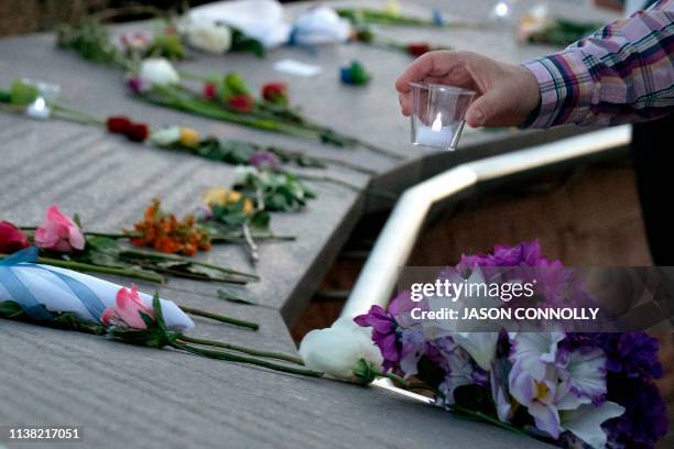 Visitor places a candle among flowers at the Columbine Memorial at Clement Park in Littleton, Colorado, during a community vigil for the 20th...