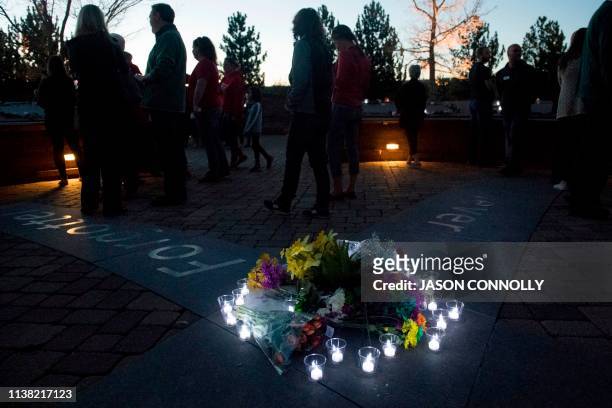 Candles wrap around a collection of flowers at the Columbine Memorial at Clement Park in Littleton, Colorado, during a community vigil for the 20th...