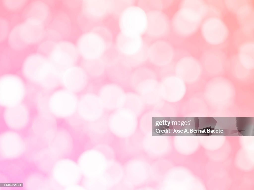 Close-up unfocused lights in the shape of circles of light pink background.