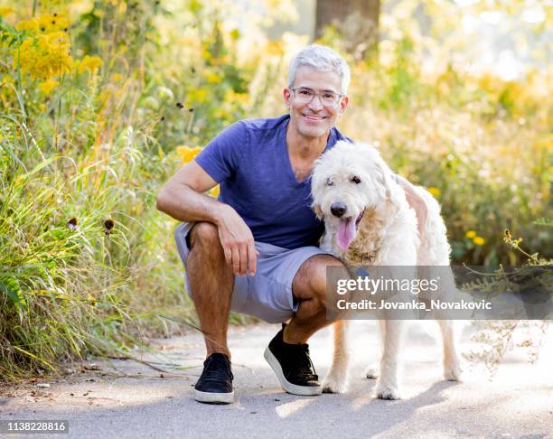 glimlachende senior man knuffelen hond - hairy old man stockfoto's en -beelden