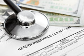 Stethoscope with money on health insurance claim form.