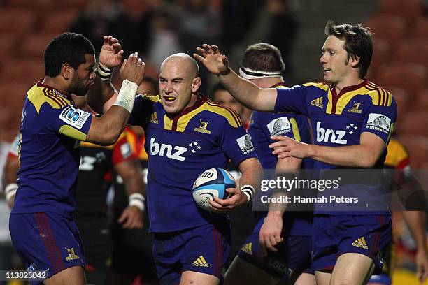 Jason Rutledge of the Highlanders celebrates with Alando Soakai and Ben Smith after scoring during the round 12 Super Rugby match between the Chiefs...