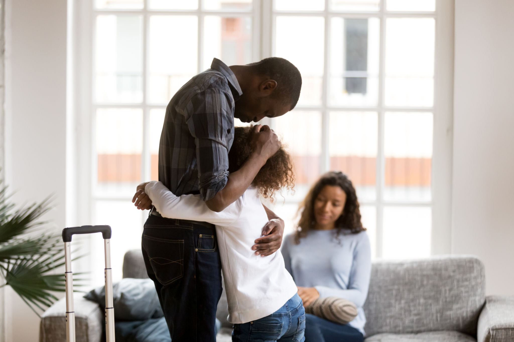 Sad African American girl hug dad leaving home with suitcase Sad African American girl hug dad leaving home with suitcase