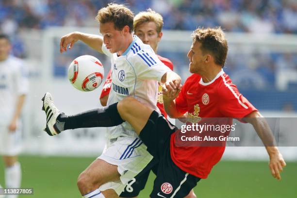 Benedikt Hoewedes of Schalke is challenged by Eugen Polanski and Lewis Holtby of Mainz during the Bundesliga match between FC Schalke 04 and FSV...