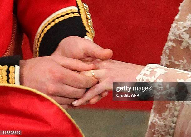 Britain's Prince William puts the ring on Kate, Duchess of Cambridge's finger during their wedding ceremony at Westminster Abbey in London on April...