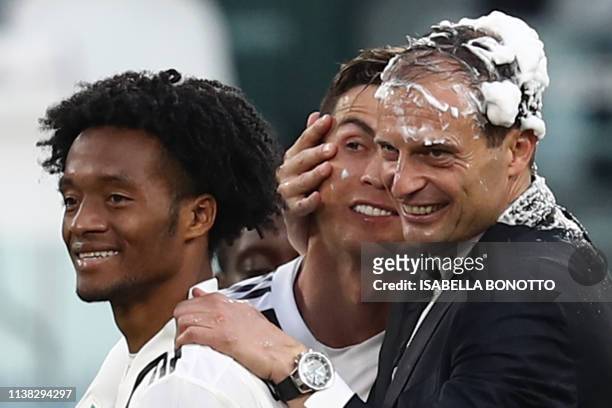 Juventus' Italian coach Massimiliano Allegri embraces Juventus' Portuguese forward Cristiano Ronaldo, both with their head covered in foam, after...