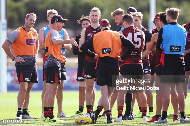 Assistant coach James Kelly speaks to players as fellow assistant coach Brett Rutten and Bombers head coach John Worsfold listen during an Essendon...