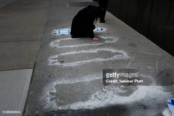 Woman makes outlines on the street of female workers near where they had fallen to their deaths at the 108th anniversary ceremony for the victims of...