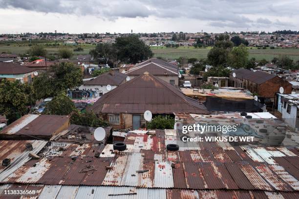 Bricks and car tyres are seen on top of the roof's of buildings on April 5, 2019 in Kliptown near Soweto. - South Africa goes to the polls next month...