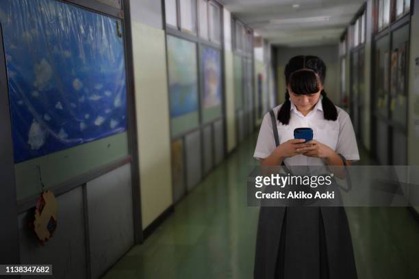 teenage girl in school uniforms using smartphone - plait ストックフォトと画像