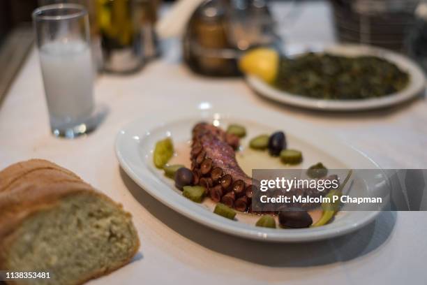cooked octopus tentacle served with olives, spinach, ouzo and bread, eresos, lesvos, greece - ouzo stock pictures, royalty-free photos & images