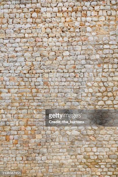 full frame shot of tall, old stone wall - steinwand stock-fotos und bilder