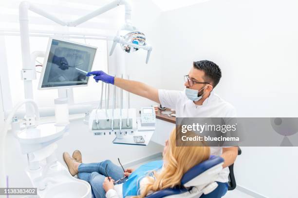 dentist explaining tooth x-rays to a female patient - dentist's chair stock pictures, royalty-free photos & images