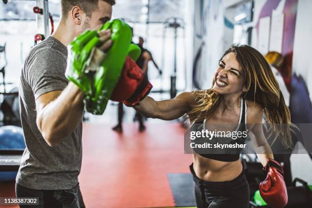 decidida mujer atlética en un entrenamiento de boxeo con su entrenador en un gimnasio. - defensa propia fotografías e imágenes de stock