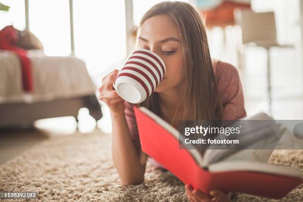 girl relaxing at home with coffee and a book - red drink stock pictures, royalty-free photos & images