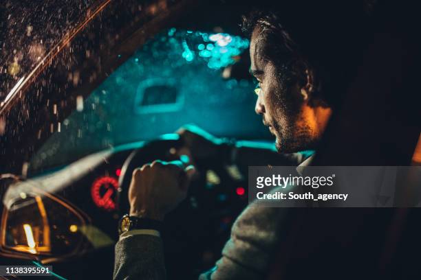 man driving a car on a rainy night - driving rain stock pictures, royalty-free photos & images