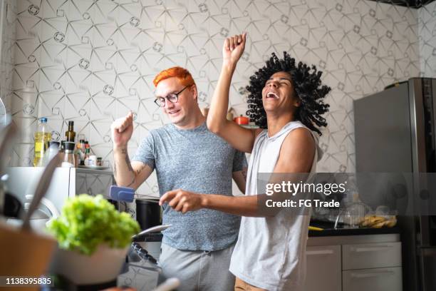 jong gay paar dansen tijdens het koken - couple dancing at home stockfoto's en -beelden