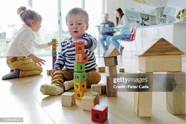 family at home, children playing with building blocks - girl strips stock-fotos und bilder