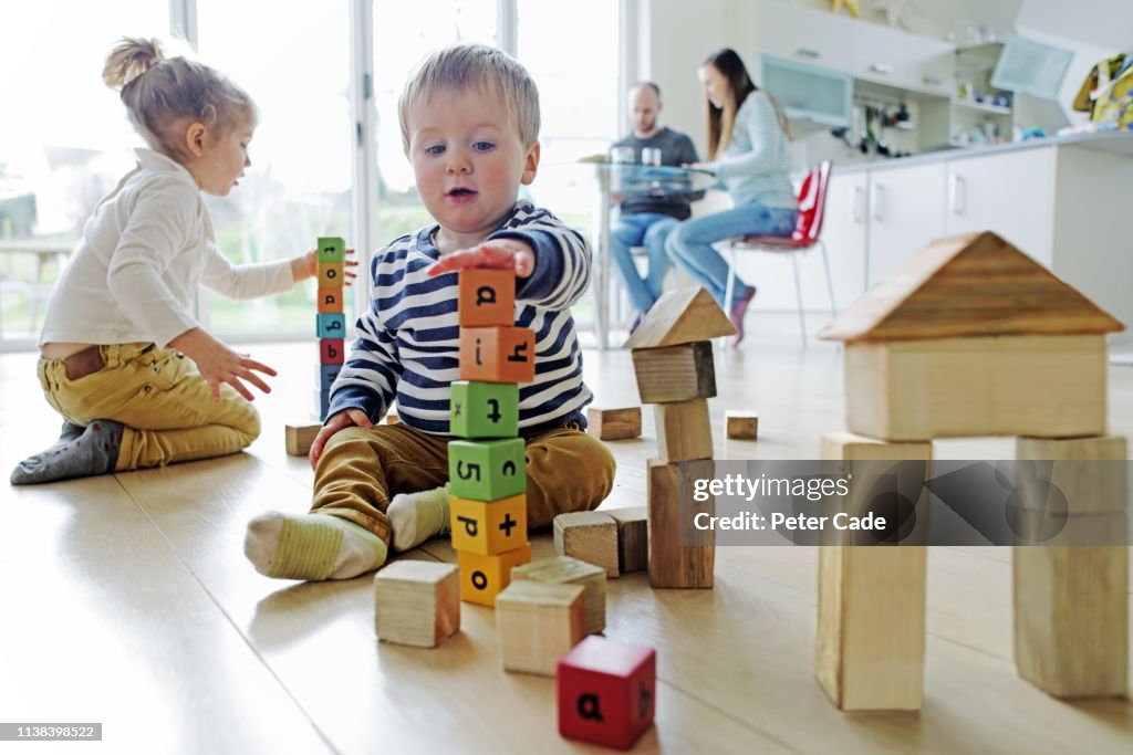 Family at home, children playing with building blocks