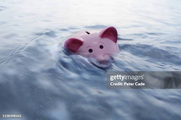 piggy bank sinking in water - preocupación financiera fotografías e imágenes de stock