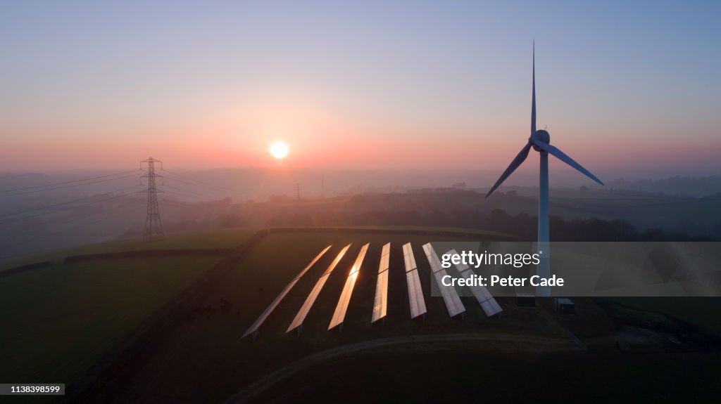 Solar panels and wind turbines in field