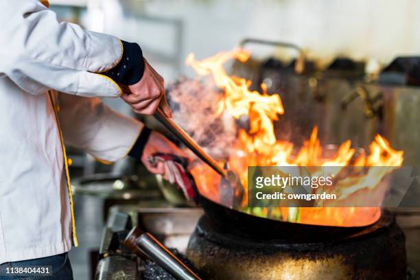 chef cocinando con llama en una sartén sobre una estufa de cocina - comida china fotografías e imágenes de stock