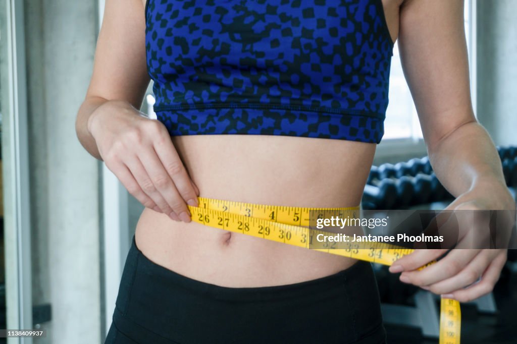 Woman measuring perfect shape of beautiful waist, healthy lifestyles concept