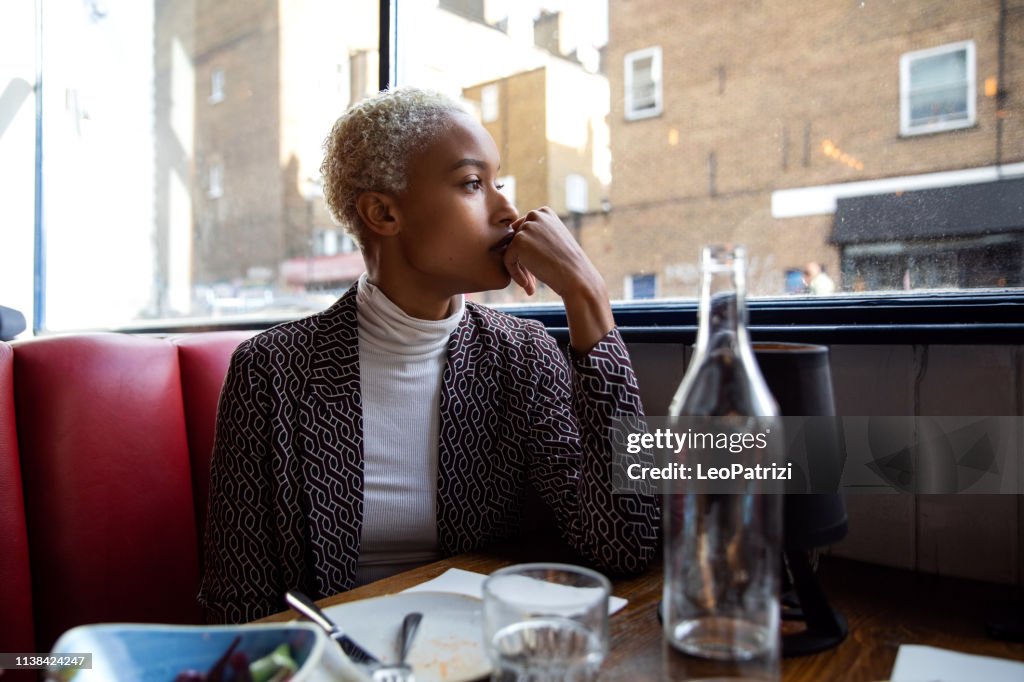 Mujer pensativa sentada sola en un restaurante a la pausa del almuerzo