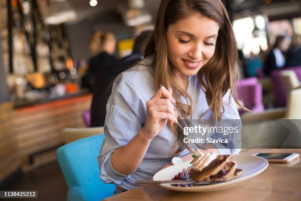 junge frau isst pfannkuchen im restaurant - eierkuchen speise stock-fotos und bilder