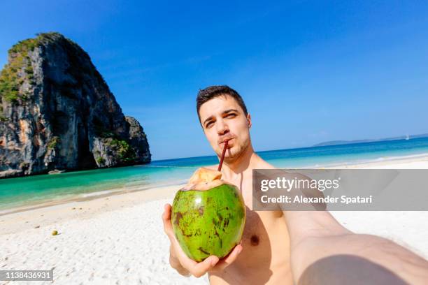 selfie of a young man drinking coconut on the beach on a sunny day - beach selfie bildbanksfoton och bilder