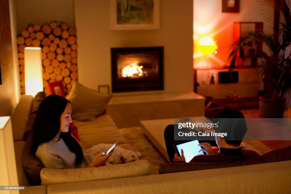 Couple using digital tablet and smart phone in living room