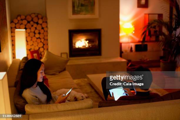 couple using digital tablet and smart phone in living room - the japanese wife stock pictures, royalty-free photos & images