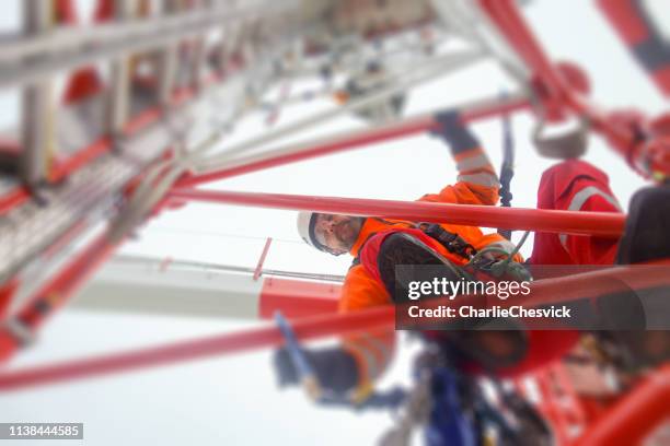 rope access technician climbing on the tower - antenna with hooks and looking down - telecom tower stock pictures, royalty-free photos & images