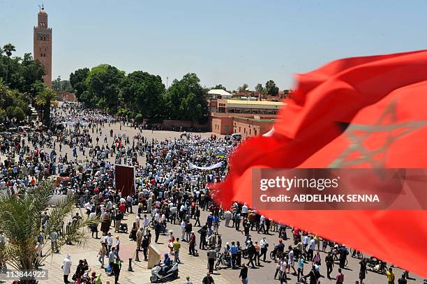 The national flag of Morocco flies as people gather for a demonstration by the February 20 movement in Marrakesh on May 8, 2011 to denounce terrorism...