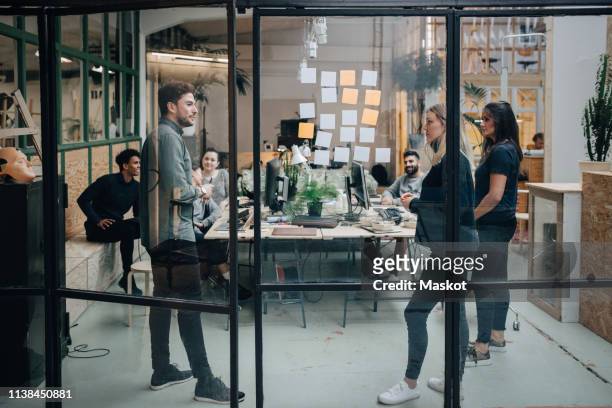 business colleagues brainstorming in meeting at office seen through glass wall - brainstorming stock pictures, royalty-free photos & images