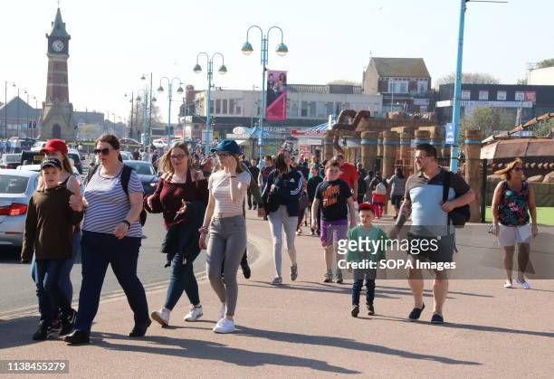 People seen walking towards the beach front past the amusements on offer during Easter. People enjoy the unseasonably warm Easter weather in the UK -...