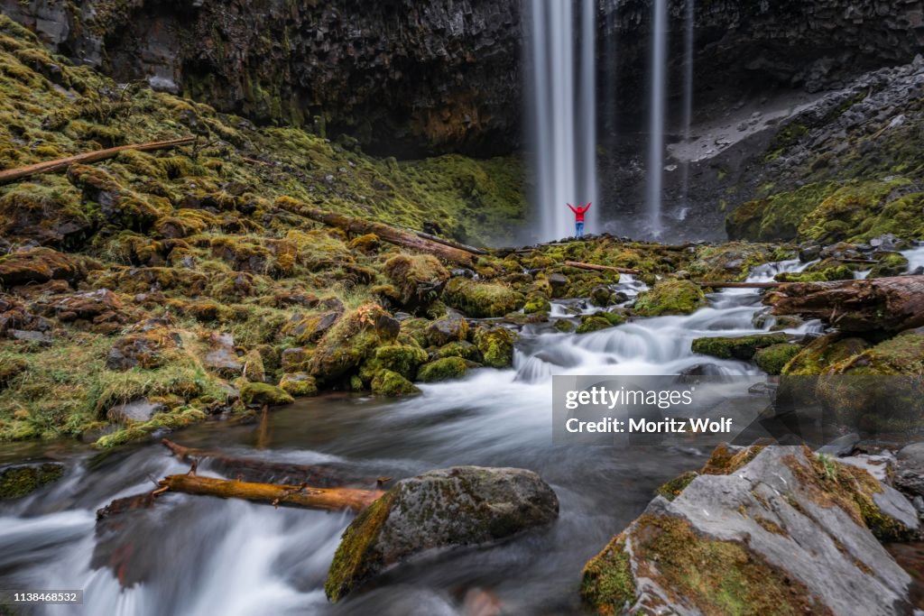 Hiker in front of a high waterfall, water falls over a rocky outcrop, Tamanawas Falls, wild river Cold Spring Creek, time exposure, Oregon, USA