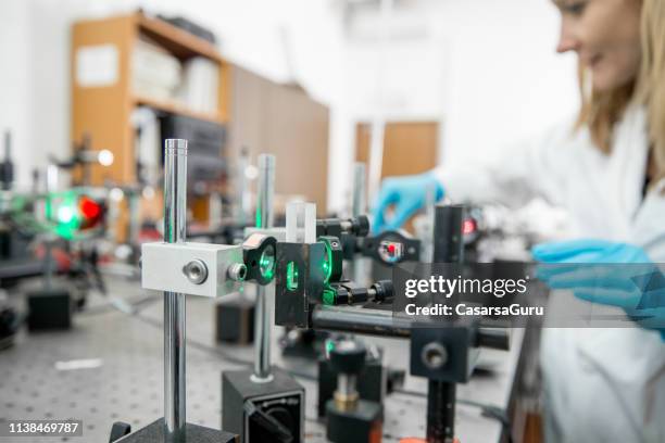 close-up of female researcher assembling laser experimentation platform part - laser experiment stock pictures, royalty-free photos & images