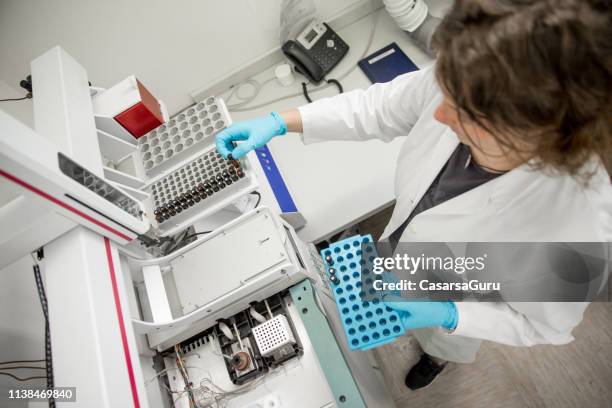 weibliche forscherin putting vials in den autosampler holder – gas-chromatographie - wissenschaftliche-probe stock-fotos und bilder