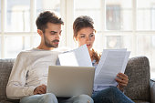 Focused couple sitting on couch reading received formal letter