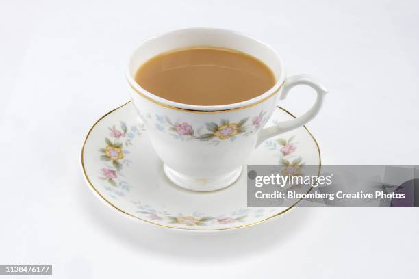 a cup of tea in a china tea cup and saucer - ティーカップ ストックフォトと画像